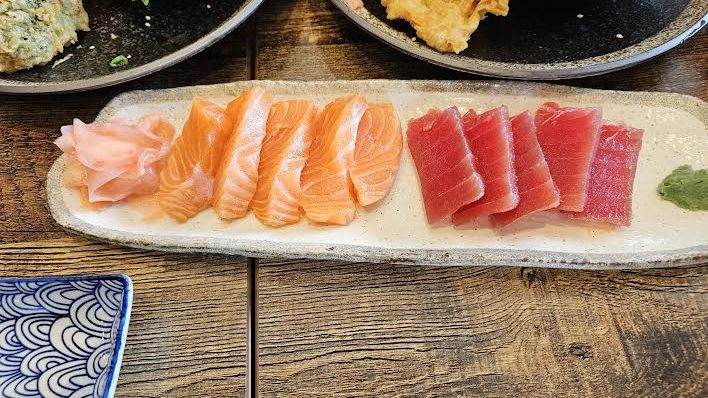 5 pieces of salmon and tuna on a long white plate