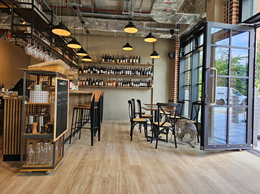 part of restaurant with tables and shelves of wine